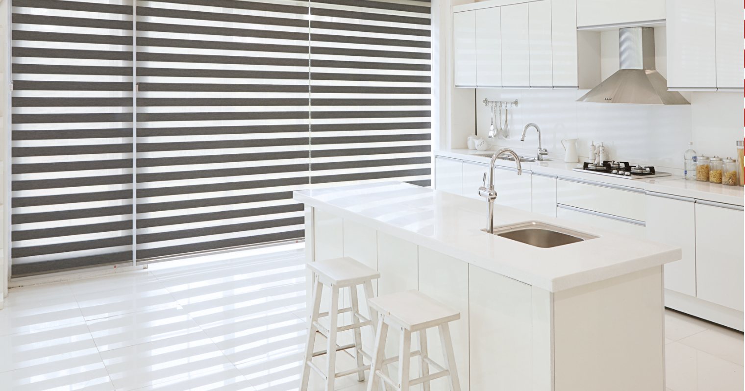 Grey zebra shades with alternating sheer and solid bands in a white kitchen